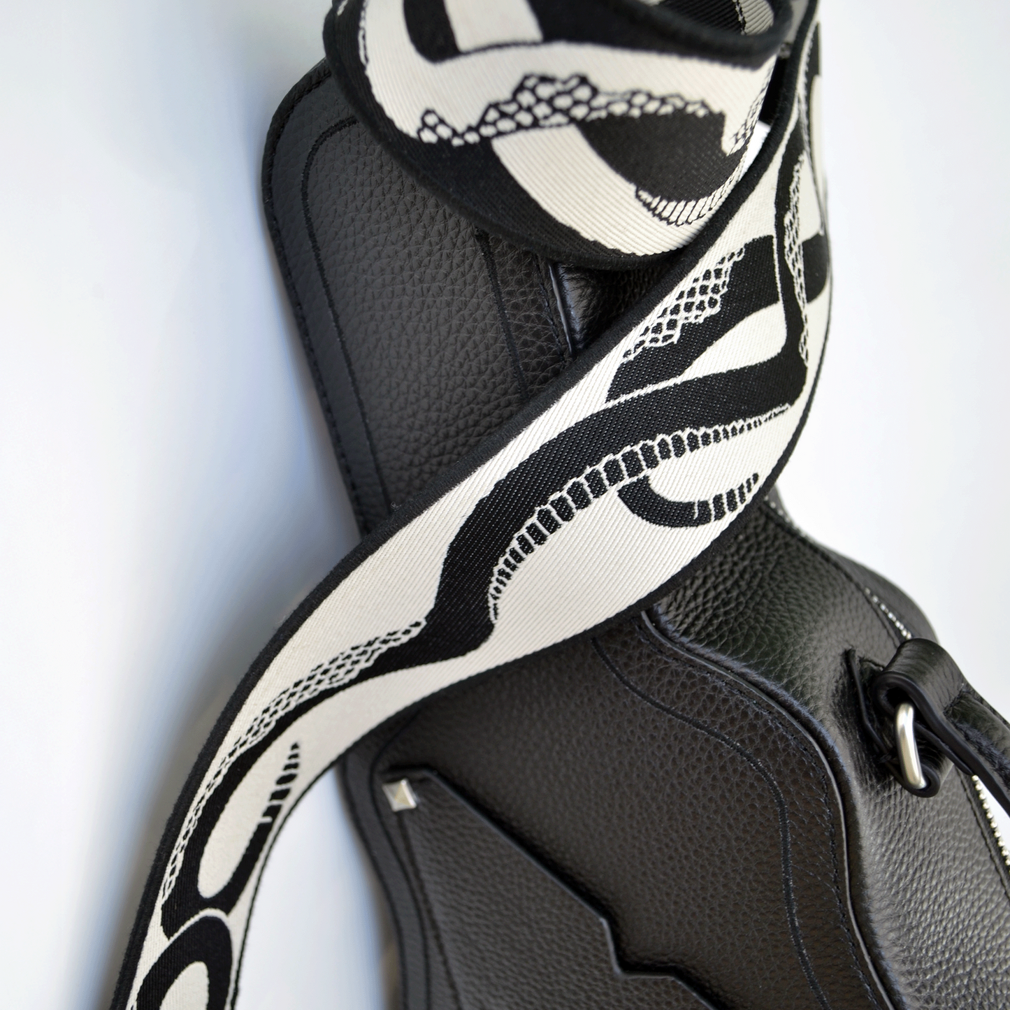 Ivory (white) side of reversible snake jacquard guitar strap styled with black Mary and Shelley Ritual Bag.
