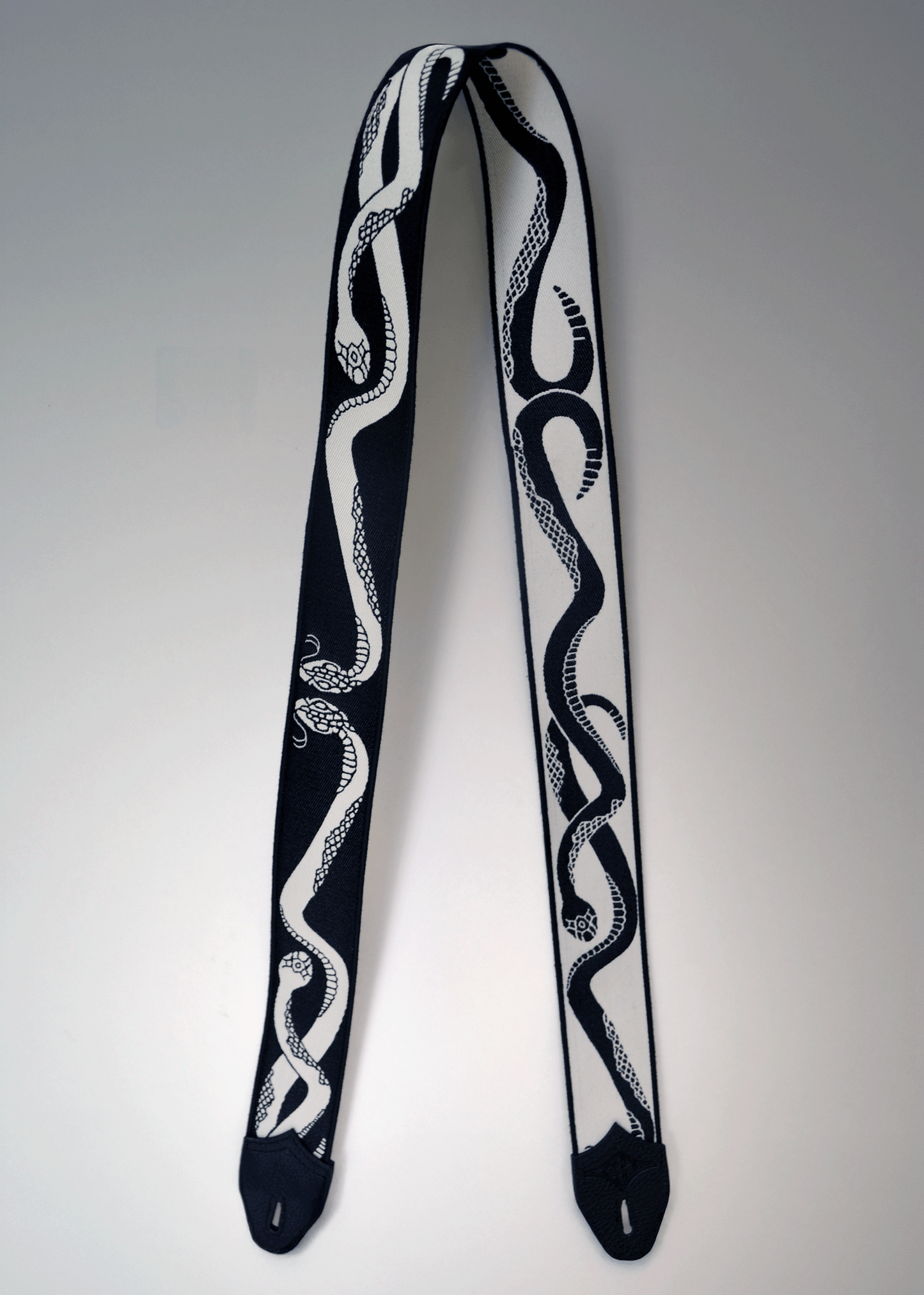Reversible black and ivory snake jacquard guitar strap with black leather endcaps by Mary and Shelley