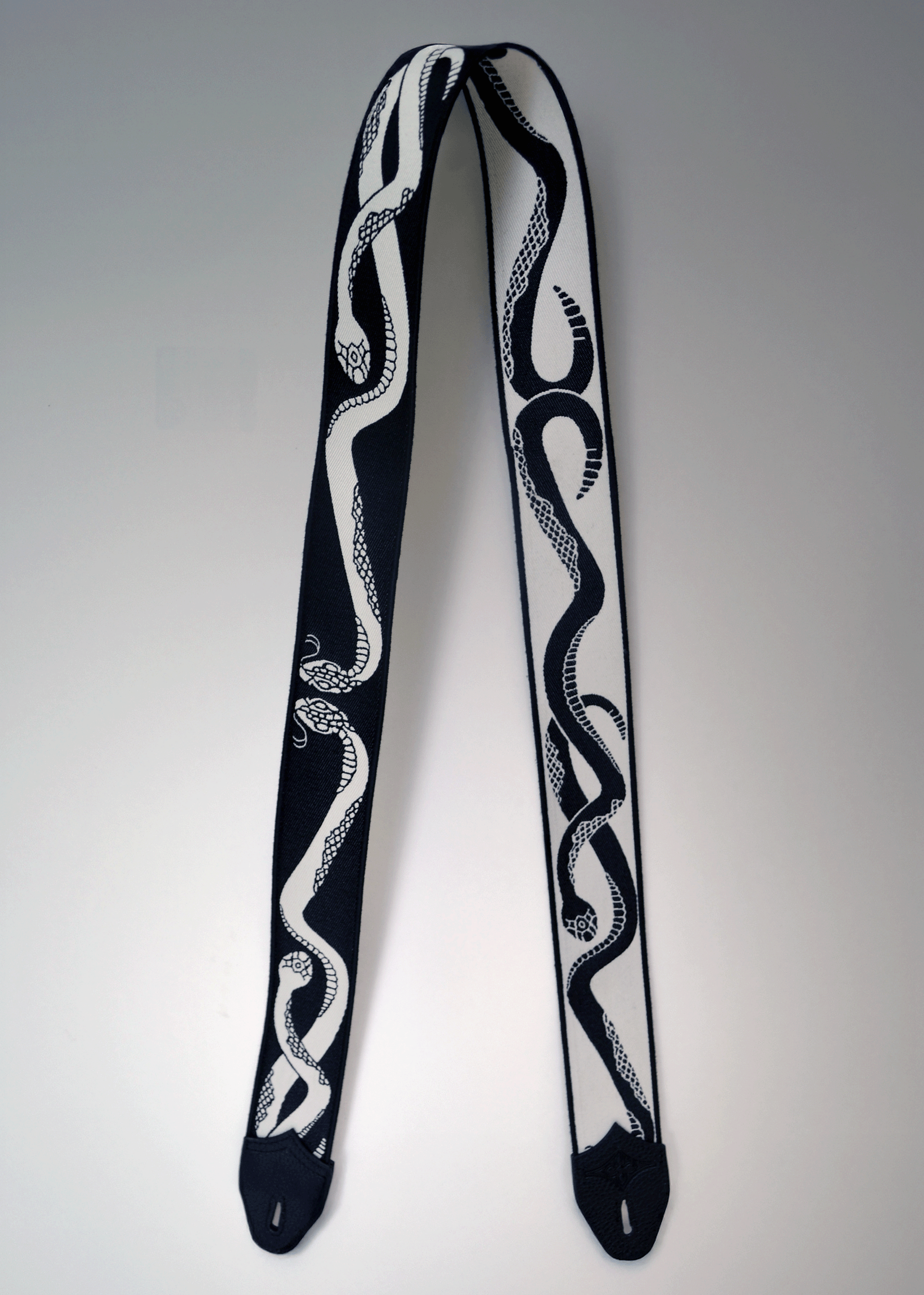 Reversible black and ivory snake jacquard guitar strap with black leather endcaps by Mary and Shelley