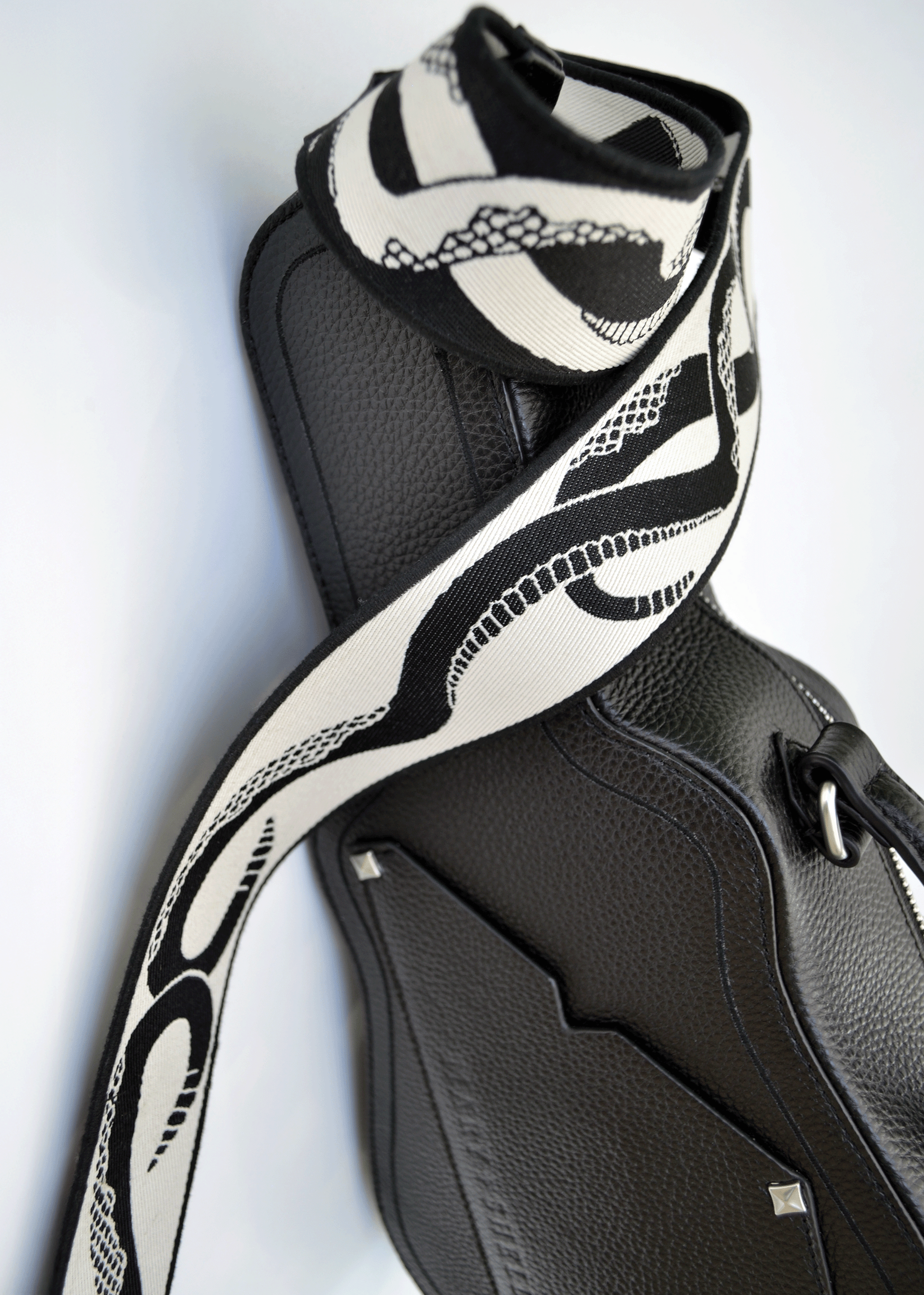 Ivory (white) side of reversible snake jacquard guitar strap styled with black Mary and Shelley Ritual Bag.