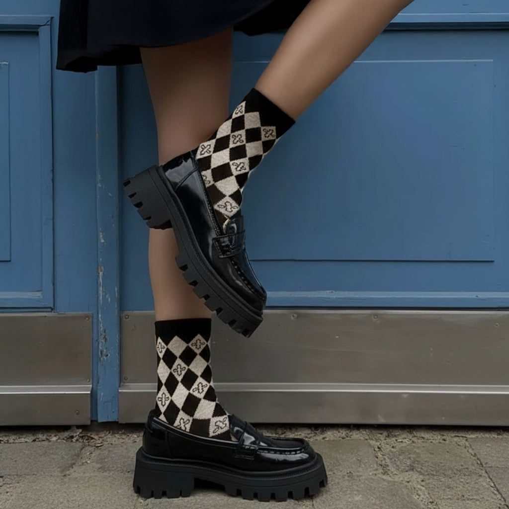 Person wearing black chuny loaders and black and grey harlequin diamond socks against a blue door background
