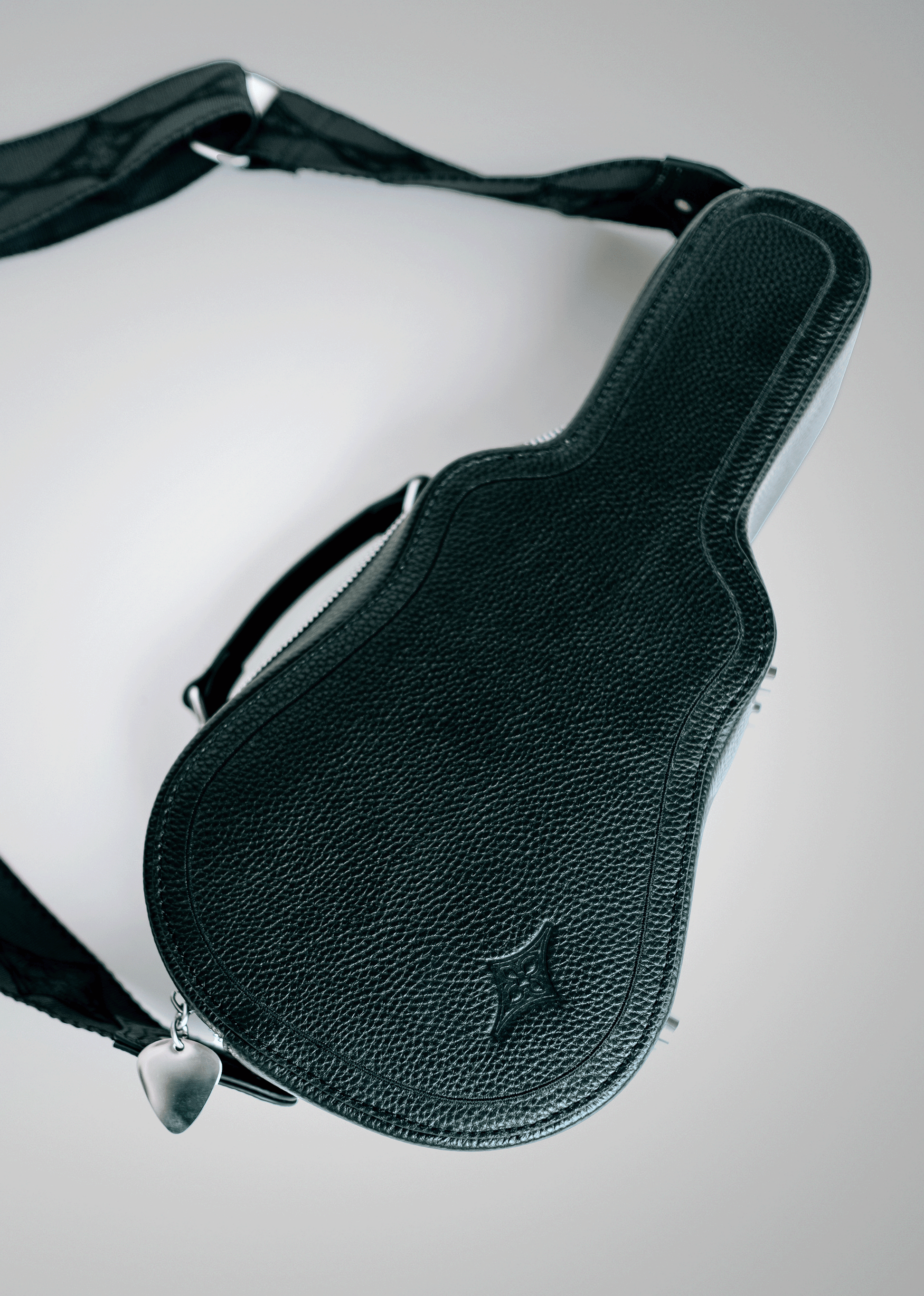 Black Mary and Shelley Ritual Crossbody Bag with guitar case silhouette, embossed logo detail, and metal guitar pick zipper pull.